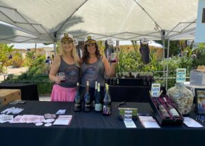 Elkhorn Peak event booth with two women in branded tank tops and sailor hats standing behind a table of wine offerings and promotional materials.